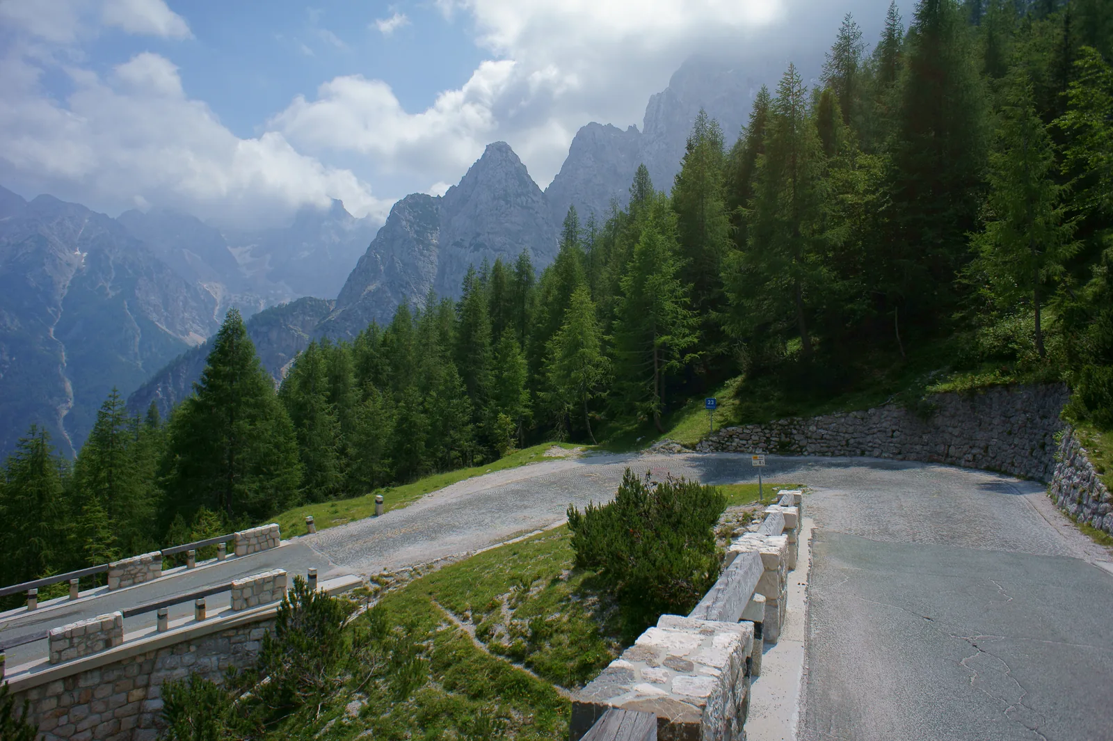 The road to the Vršič Pass in Triglav National Park, with a stone wall and a hairpin bend below jagged limestone peaks