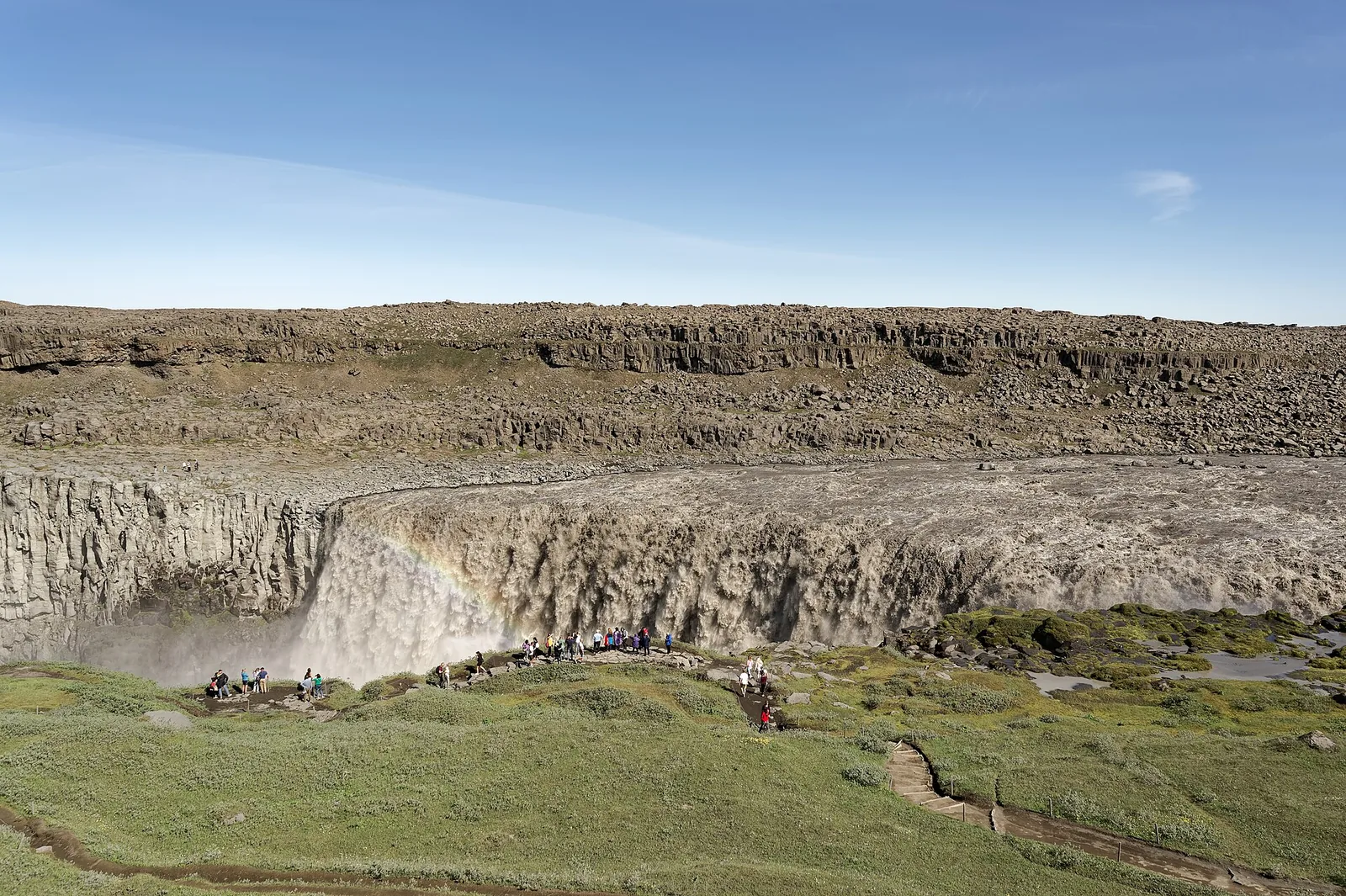 Dettifoss in the north of Vatnajökull National Park: grey masses of water plunge into a wide canyon, spray rising