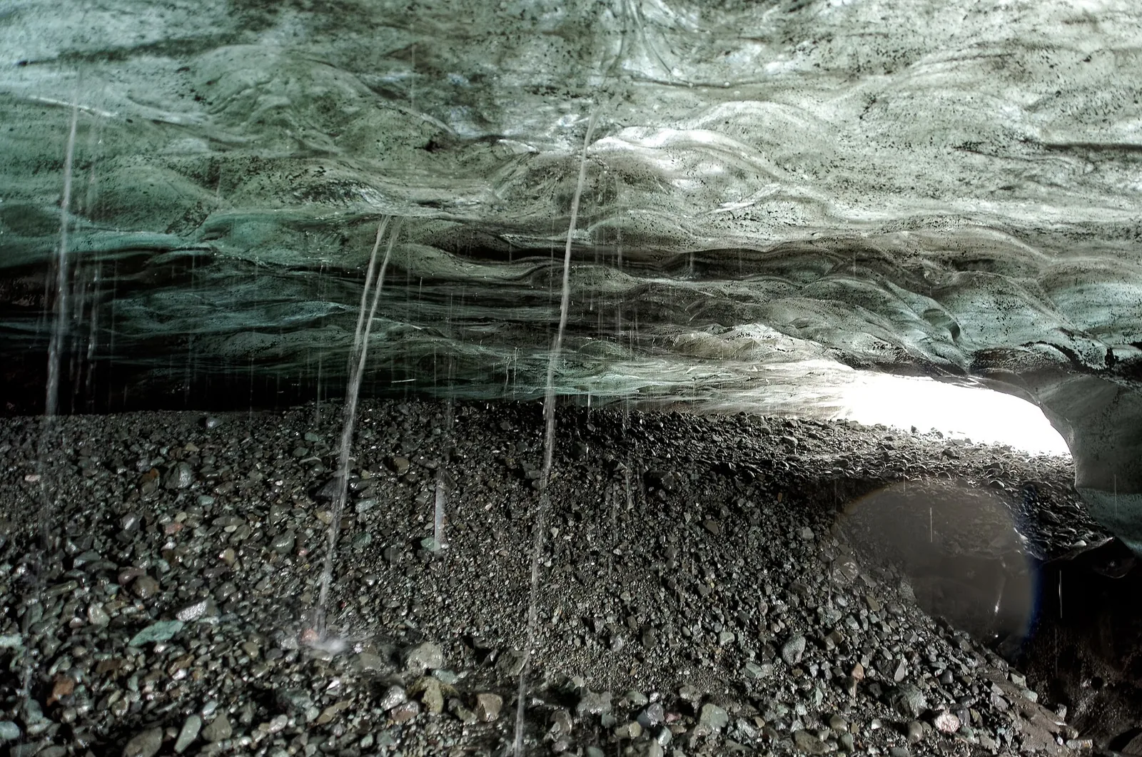Blue ice vault of an ice cave at Breiðamerkurjökull in Vatnajökull National Park, scree and meltwater on the floor