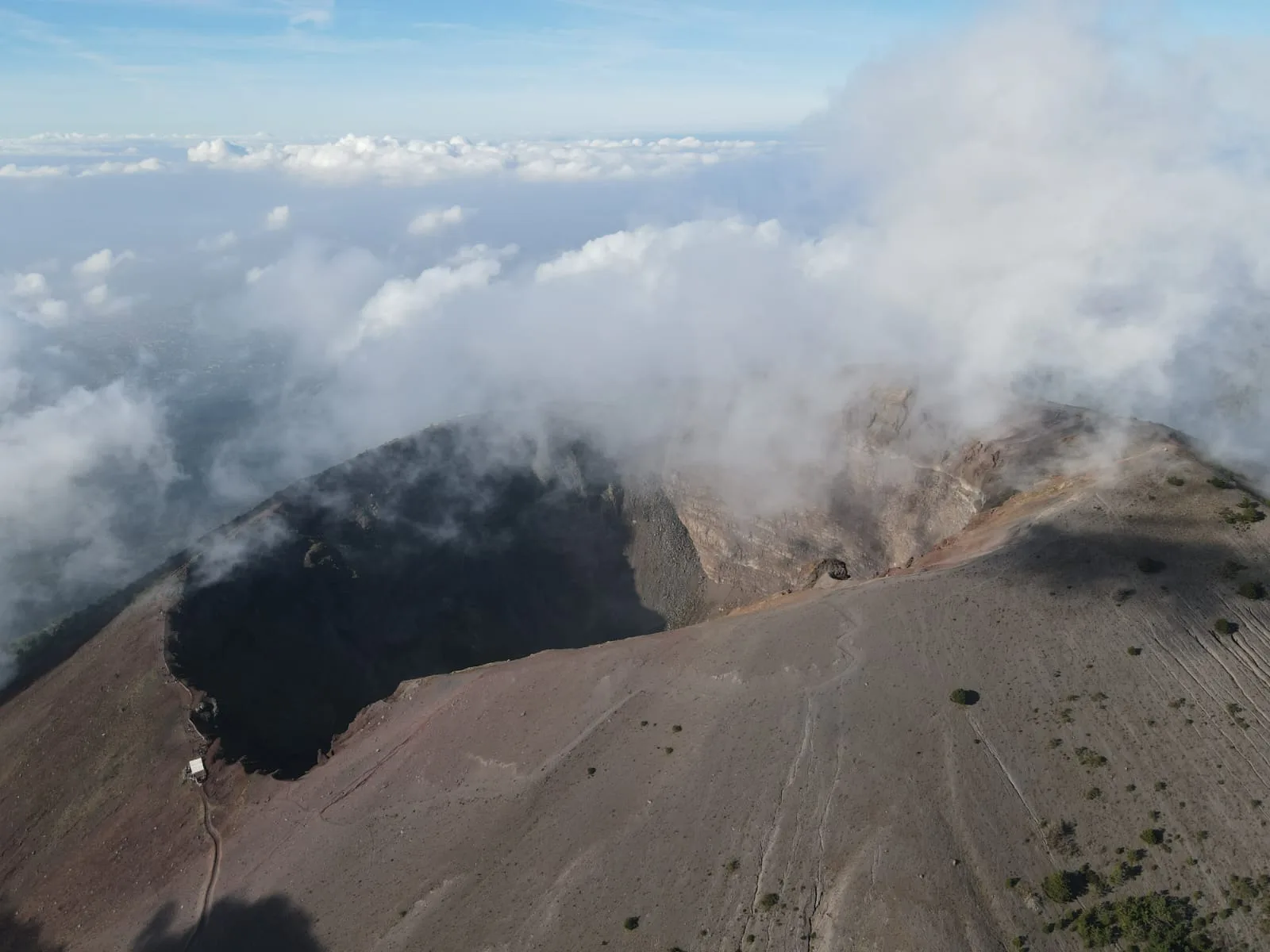 The crater of the Gran Cono in Vesuvius National Park seen from above, with clouds drifting over its rim