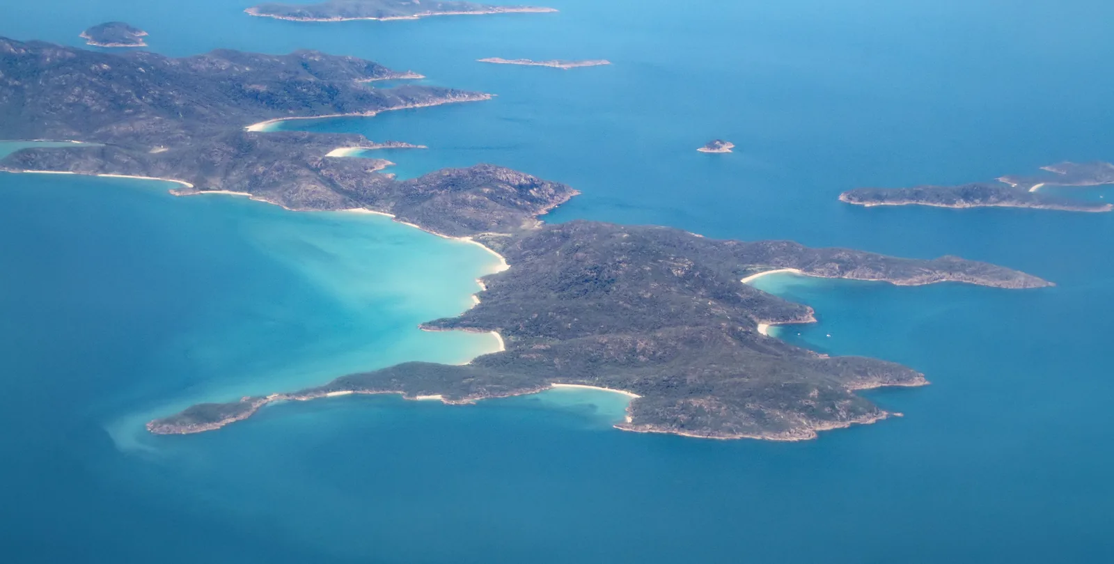 The Whitsunday Islands on the Great Barrier Reef from the air: forested islands with white beaches in a turquoise sea