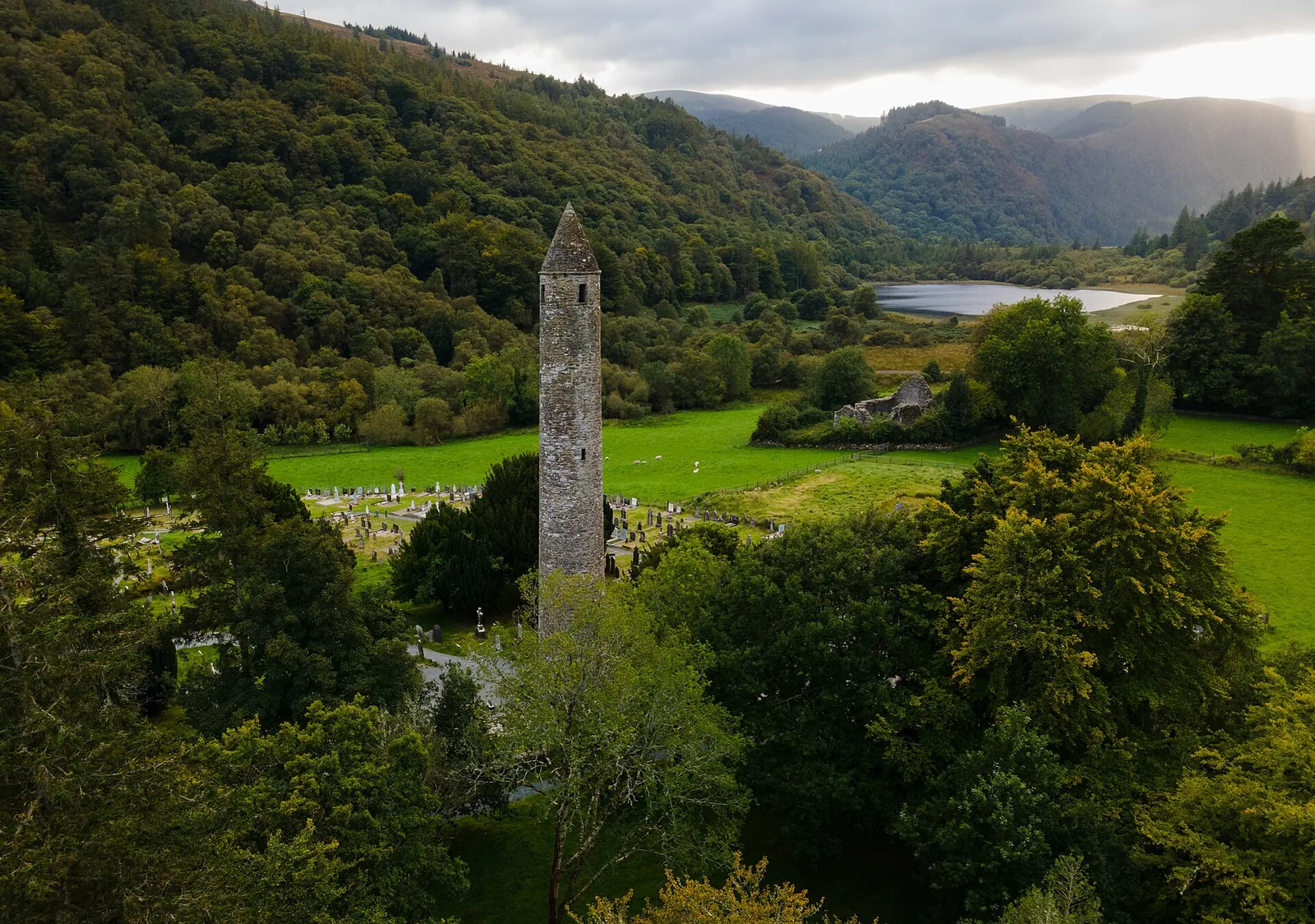 Aerial view of the monastic site of Glendalough in Wicklow Mountains National Park, with the round tower among trees and graves