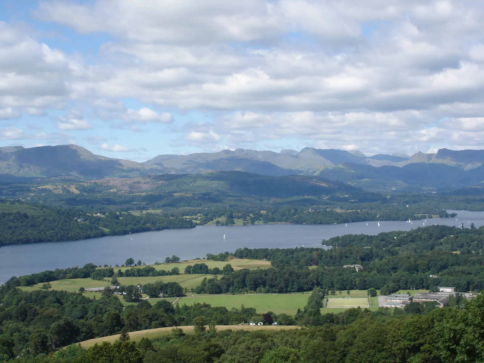 View from a hill over Windermere in the Lake District National Park, with meadows, woods and the fells beyond