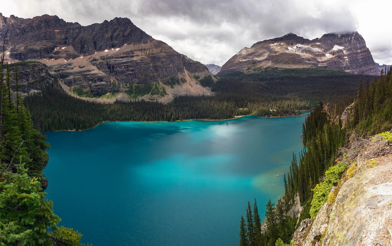 Turquoise Lake O'Hara in Yoho National Park in its rocky basin, surrounded by conifer forest